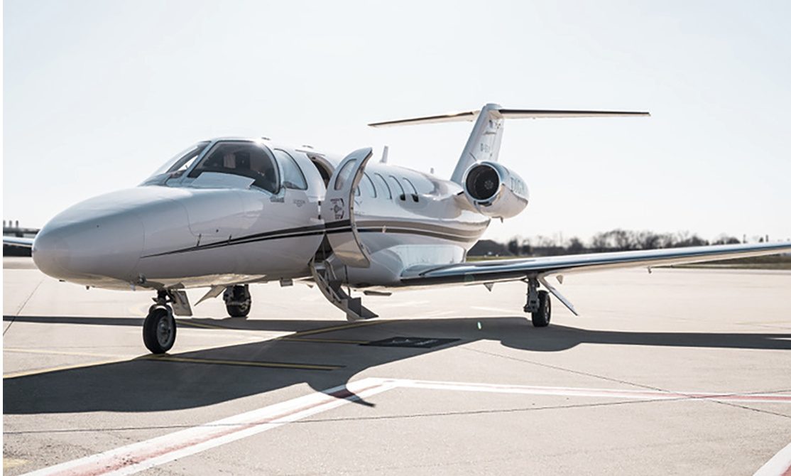 Weißer Privatjet auf dem Rollfeld bei klarem Himmel