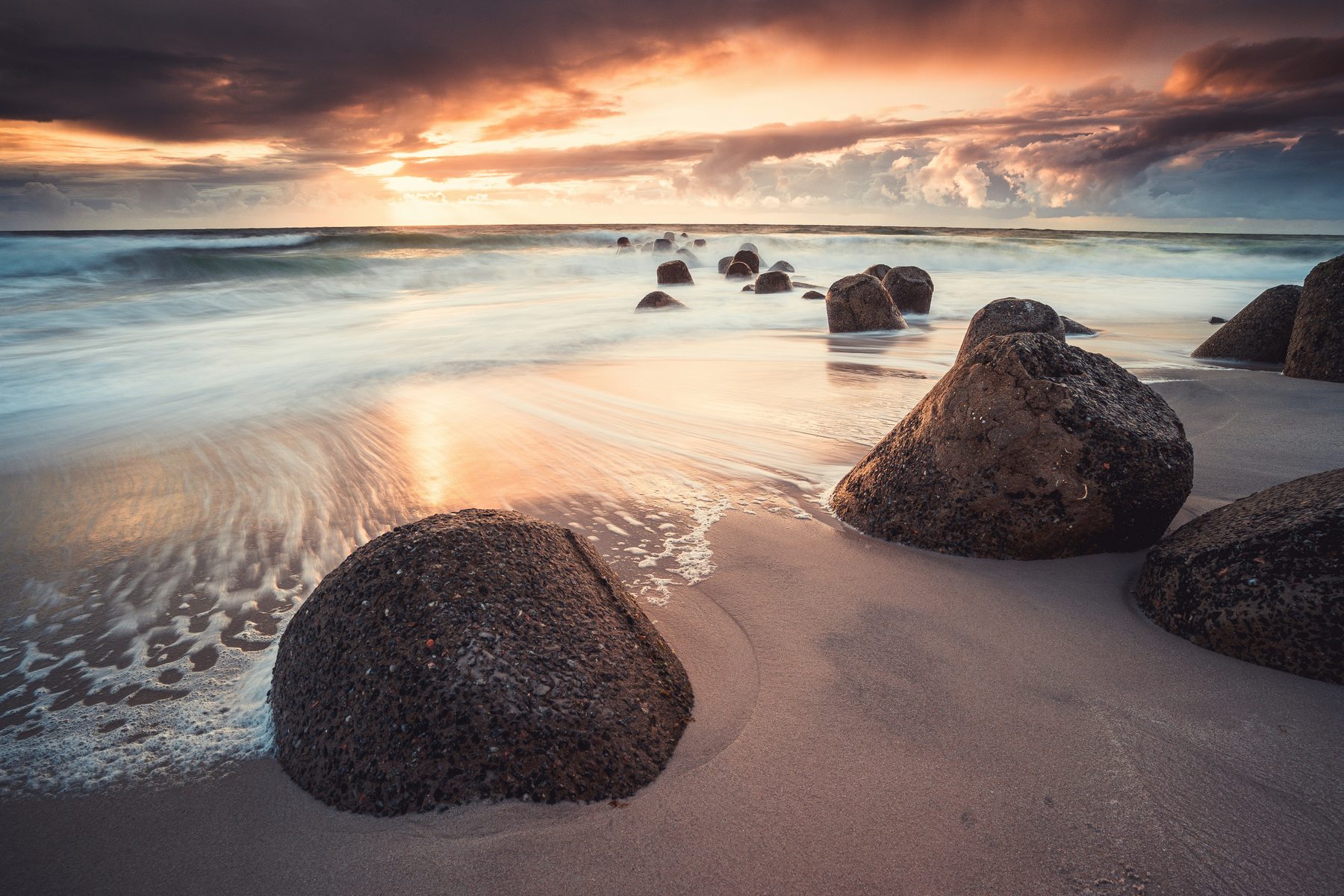 Findlinge im Wasser bei Sonnenuntergang mit dramatischem Himmel