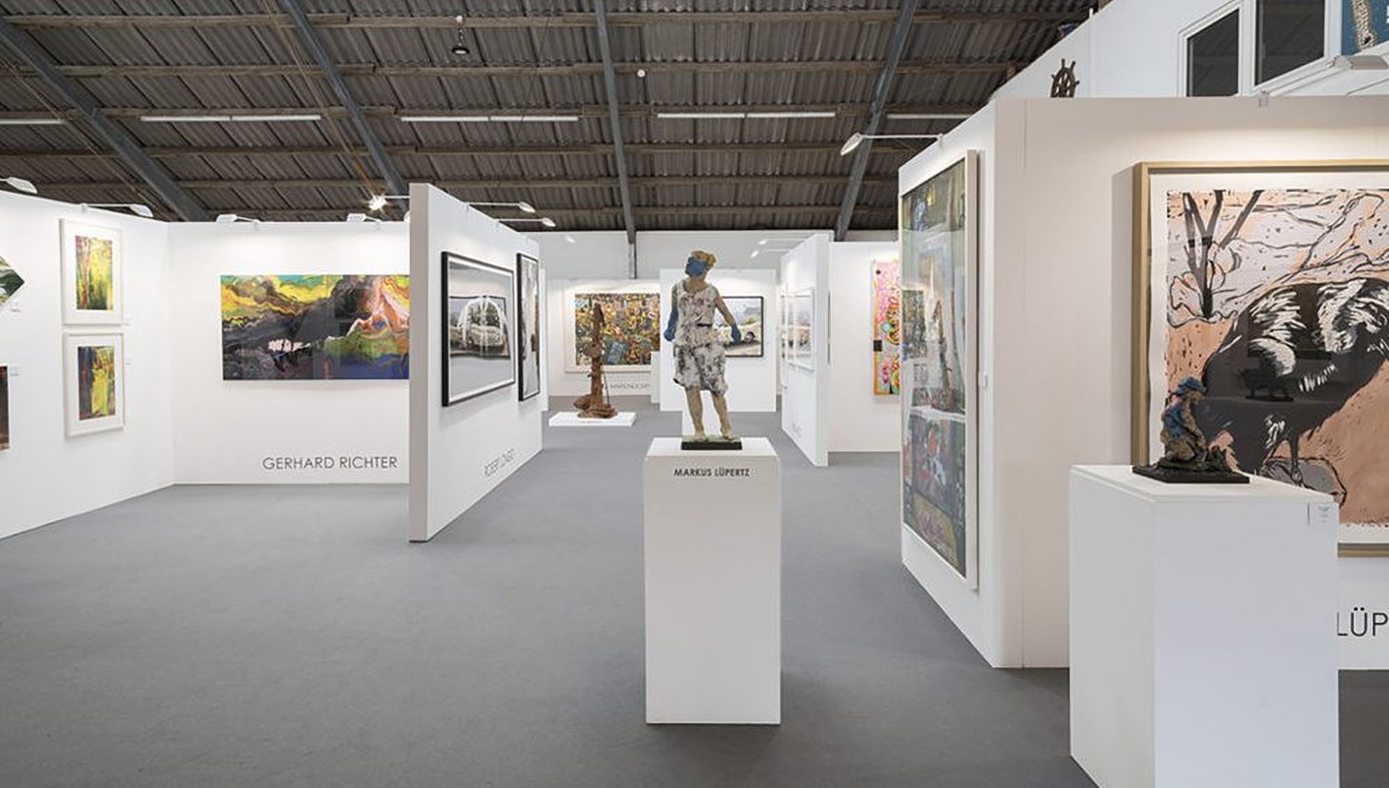 Messehalle mit Skulptur von Markus Lüpertz auf weißem Sockel, dahinter Gemälde, unter anderem von Gerhard Richter