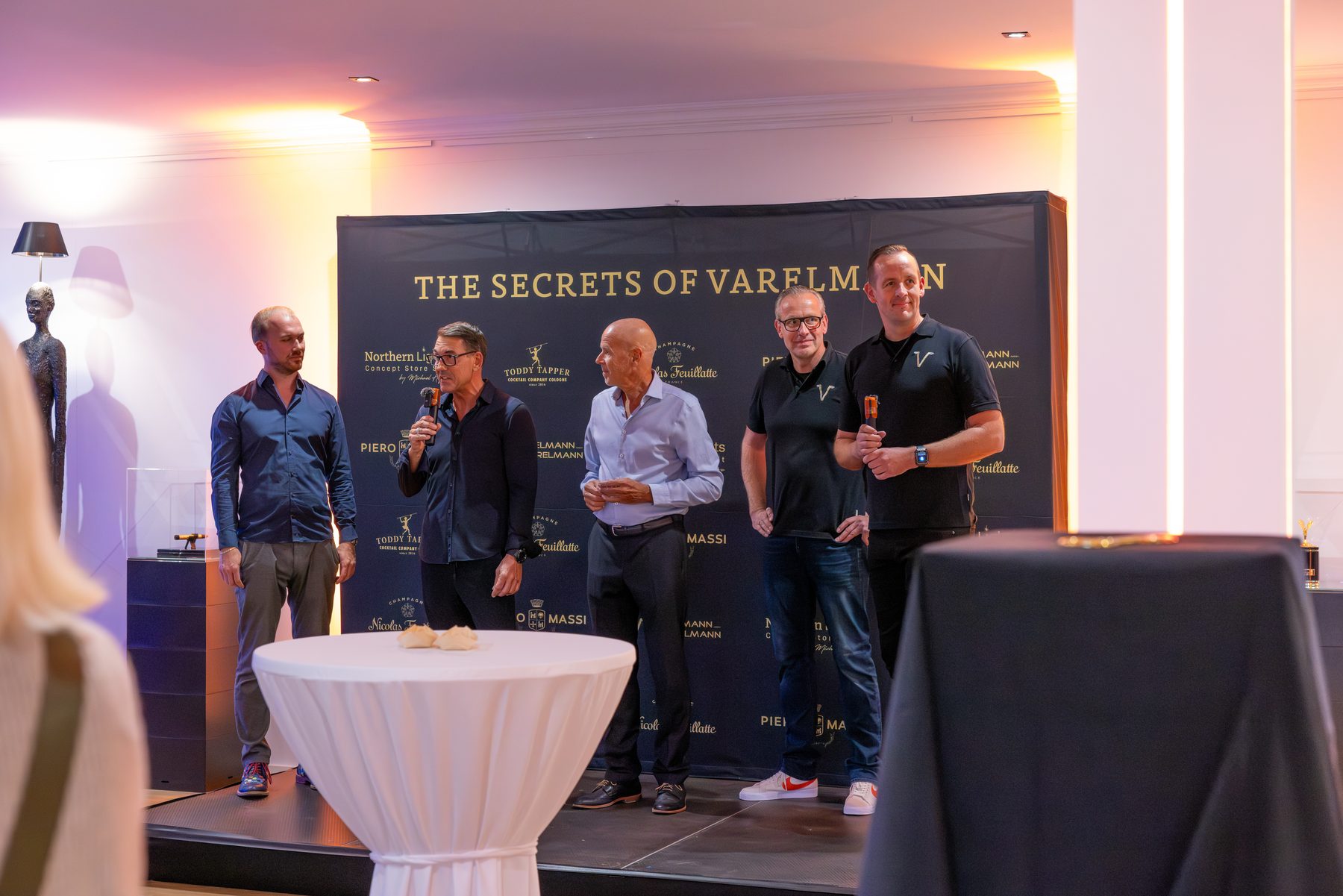 Talkrunde auf der Bühne vor der Wand „The Secrets of Varelmann“ im Concept Store