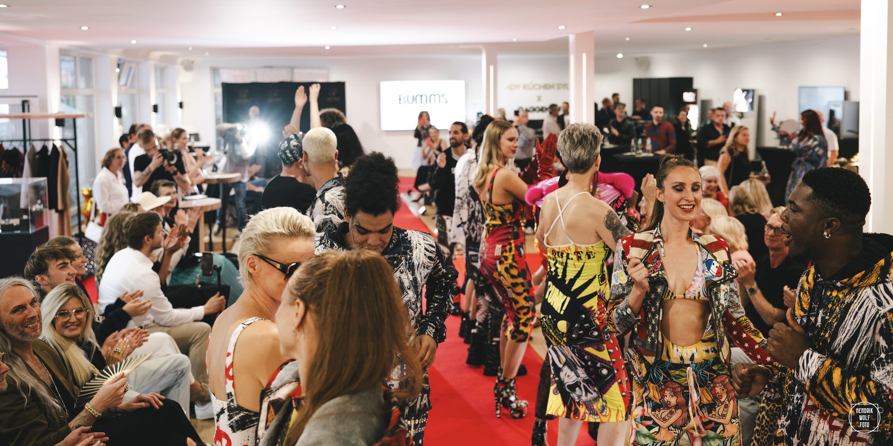 Modenschau mit bunt gekleideten Models im vollen Concept Store